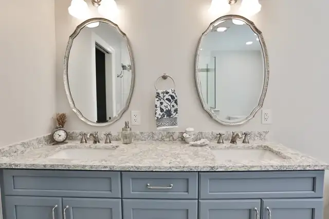 Ballard Blue bath in Saratoga Springs, NY with a blue-gray double vanity, granite top and oval silver mirrors