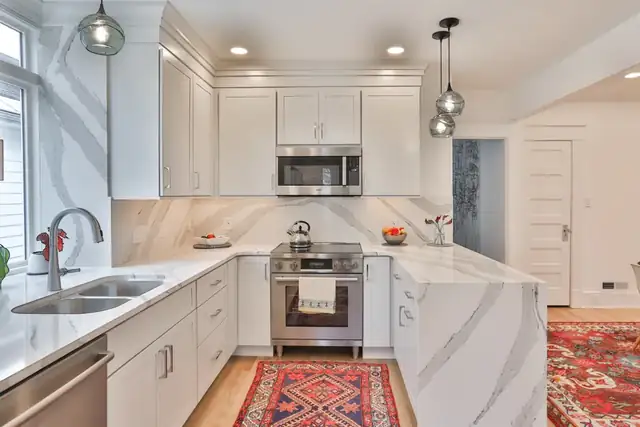 Niskayuna, NY kitchen remodel with white cabinets, quartz waterfall peninsula and full-height quartz backsplash