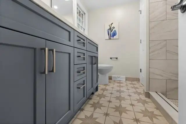 Delmar, NY bath remodel with a slate blue vanity, star pattern tile floor and large-format shower tile