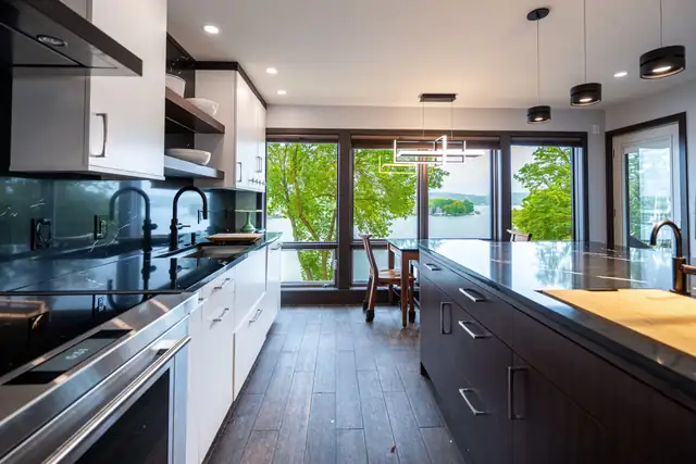Award-winning modern Saratoga kitchen with dark flat-panel cabinets, black counters, glass pendant lights and lake-view windows