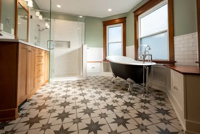 Bathroom with a black clawfoot tub, star-pattern floor tile, a glass shower, wood vanity and sage green walls