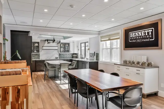 Bennett Contracting showroom with display kitchens, a wood dining table and a framed Bennett Contracting sign