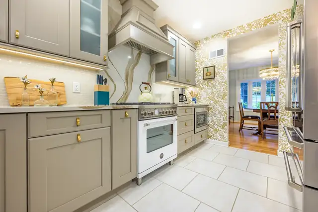 Kitchen with taupe cabinets, white range, marble slab backsplash behind the hood and a patterned accent wall